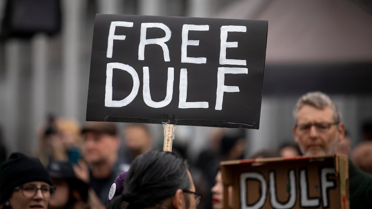 Signs are seen at a protest reading 'Free DULF'.