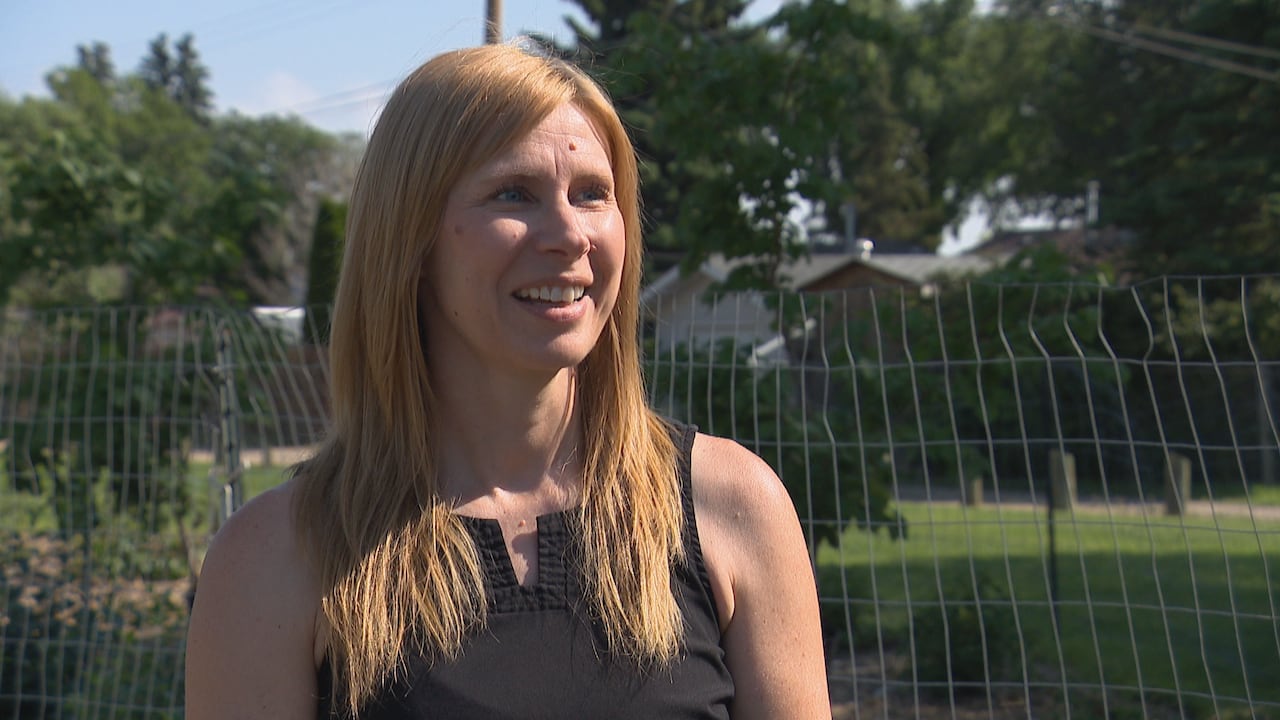 a woman speaks next to a fenced-off area in a park