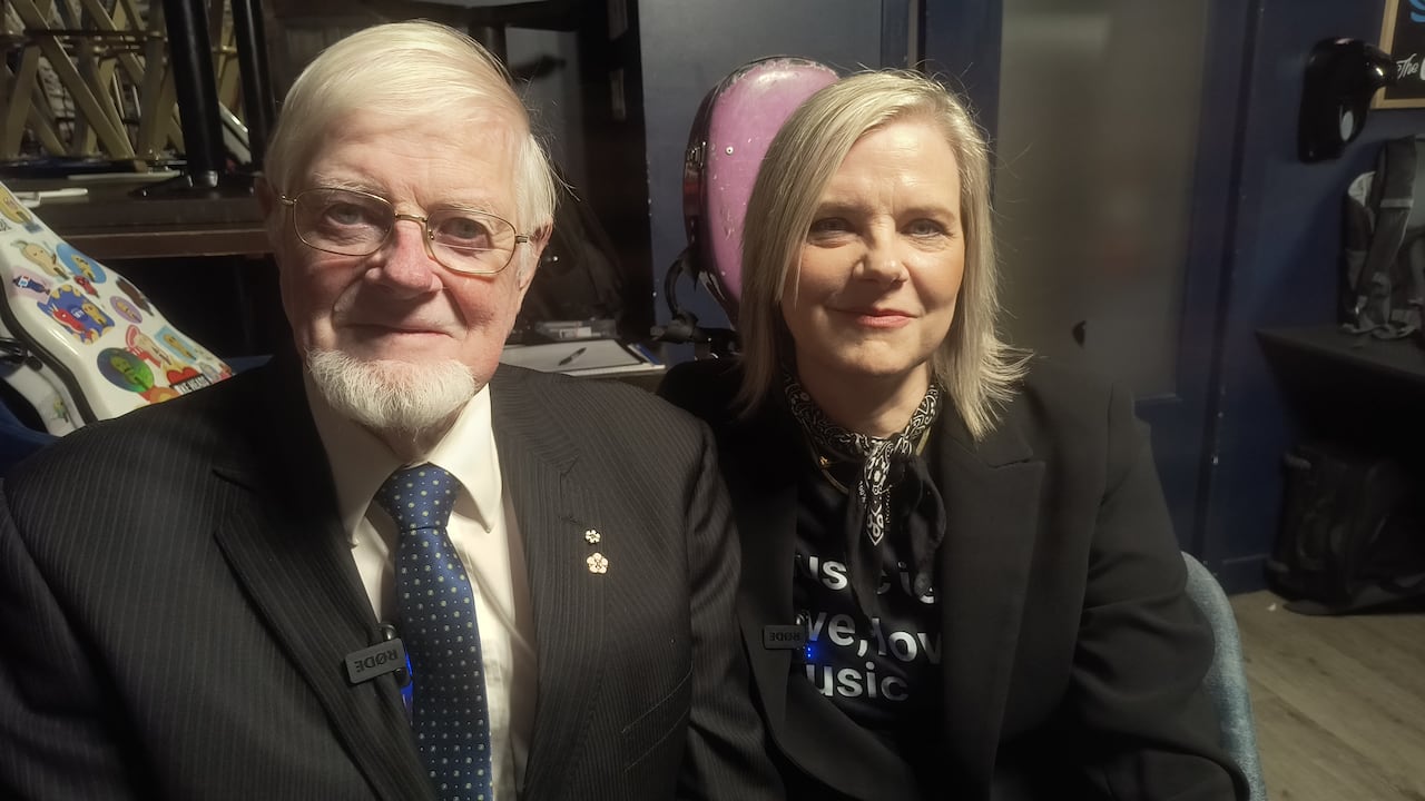a man and a woman sitting next to each other looking at the camera
