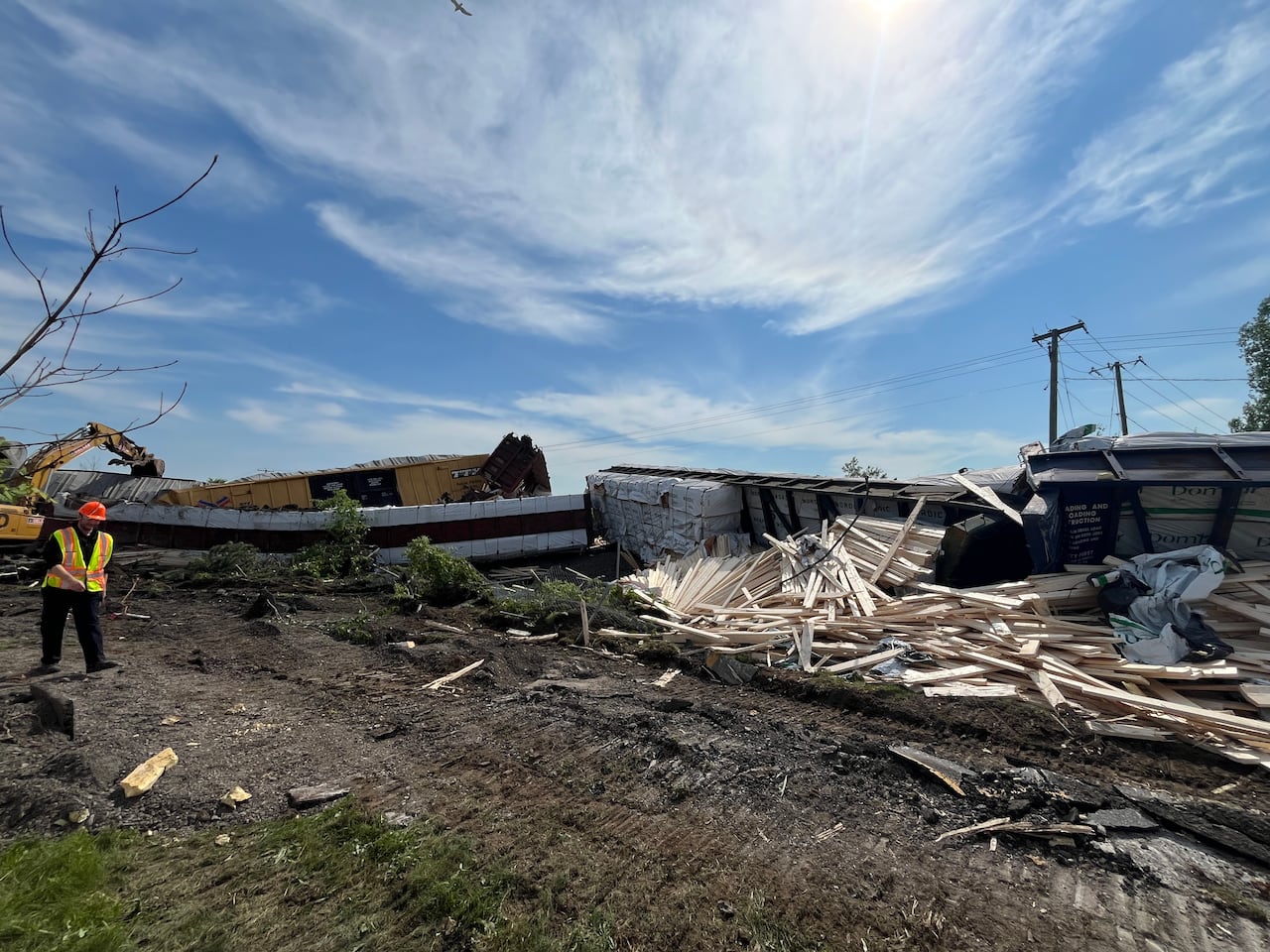Wide shot showing contents of train car flipped on its side. A worker in high-viz vest is seen on the left side of the image.