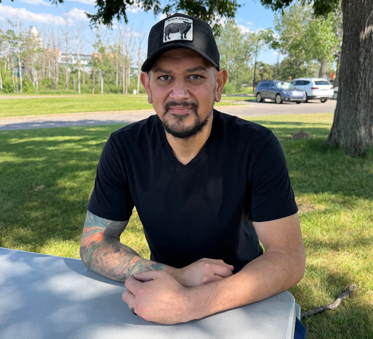 A man sitting on a bench with a ballcap and a black tshirt