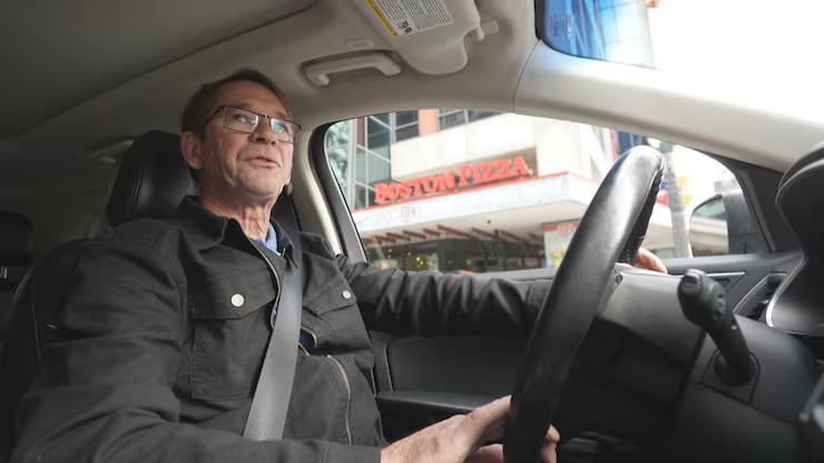 A man with glasses driving, photo taken inside of the car