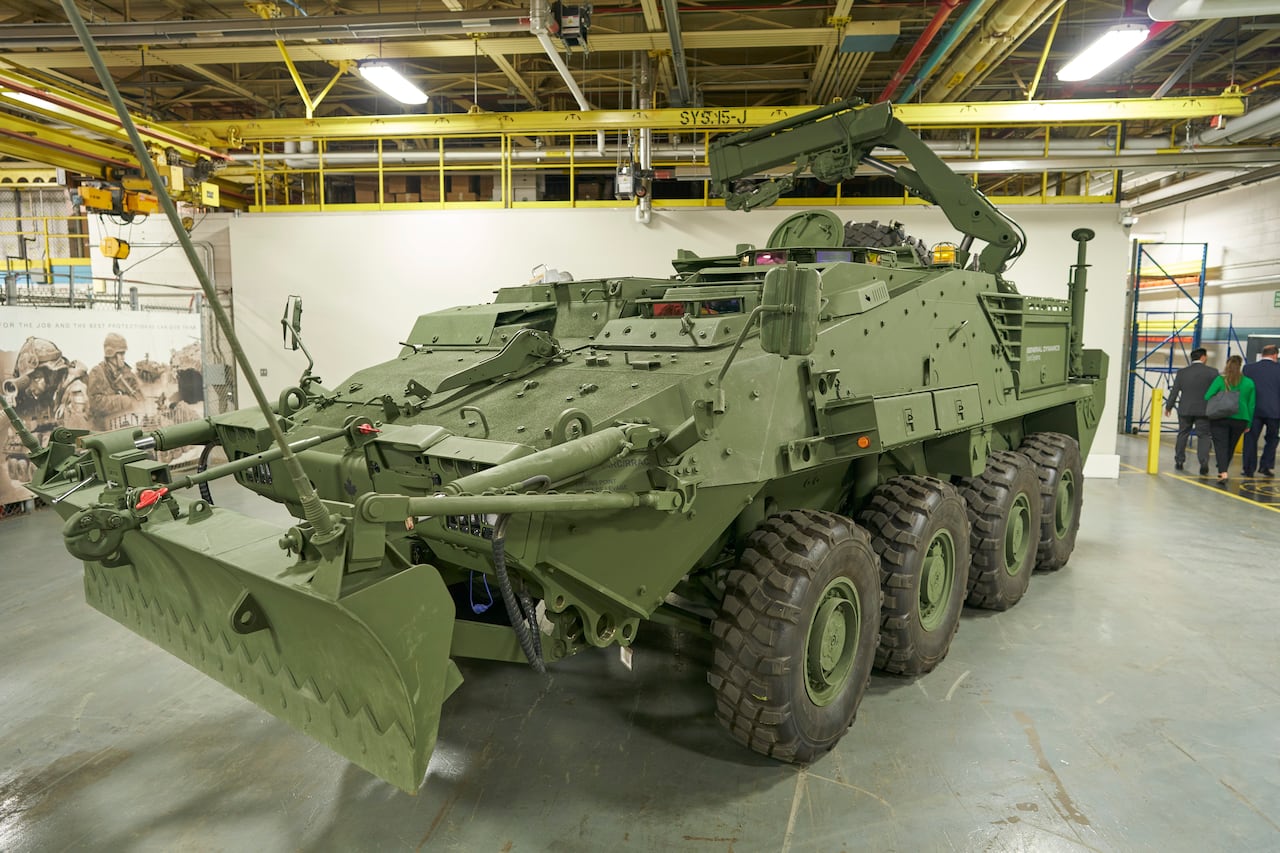 A large military vehicle is seen in a garage.