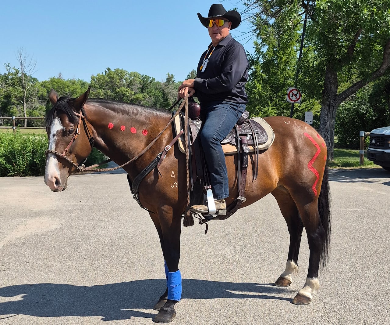 A man sits on a painted horse in a paved area.