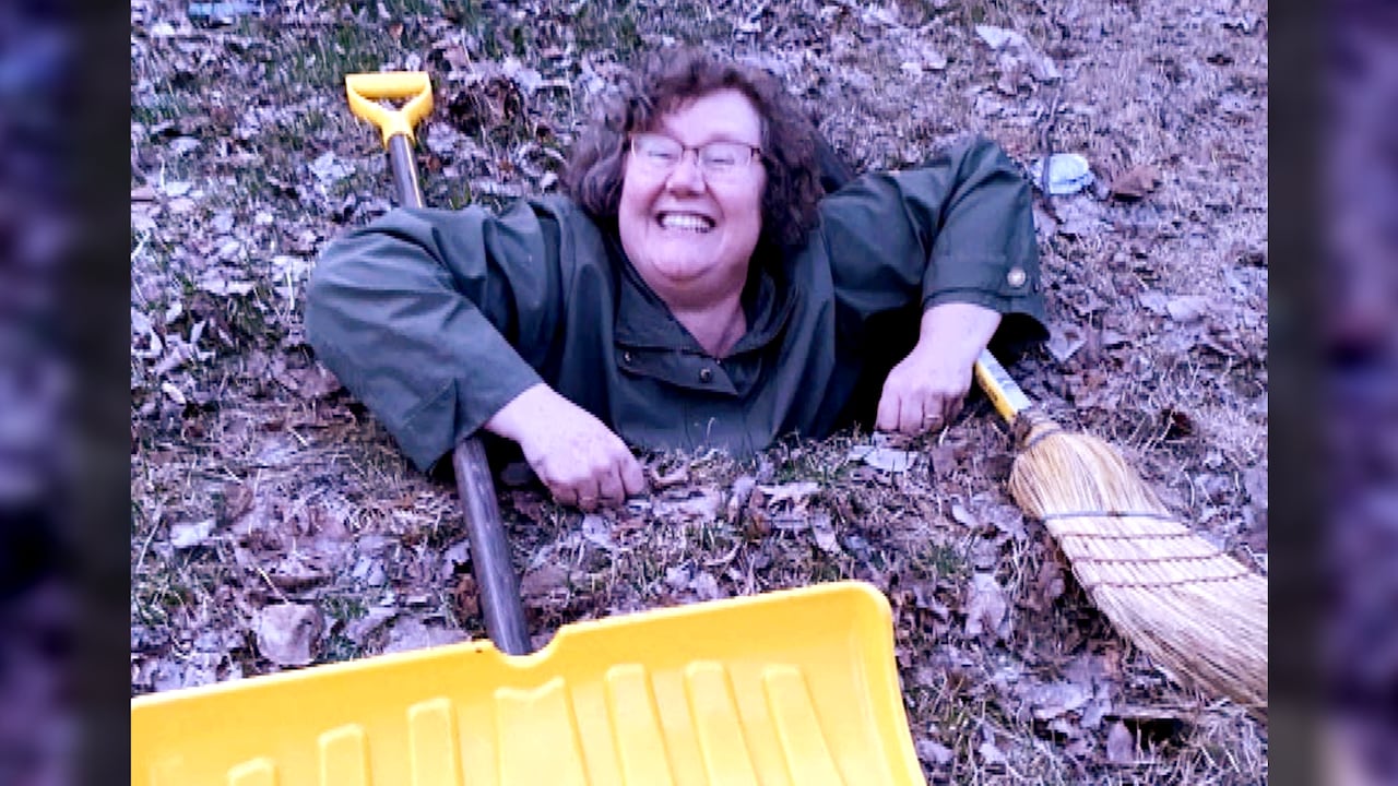 A woman smiles from inside a hole in the grassy boulevard.