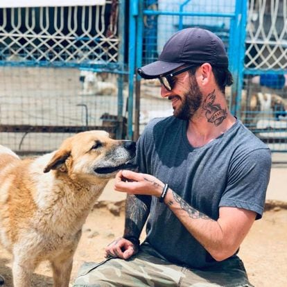A bearded man smiles next to a dog.