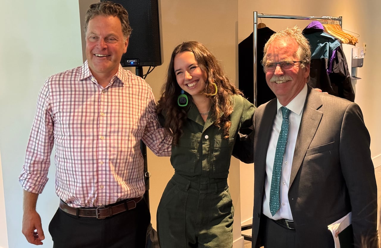 A smiling woman is flanked by two men.