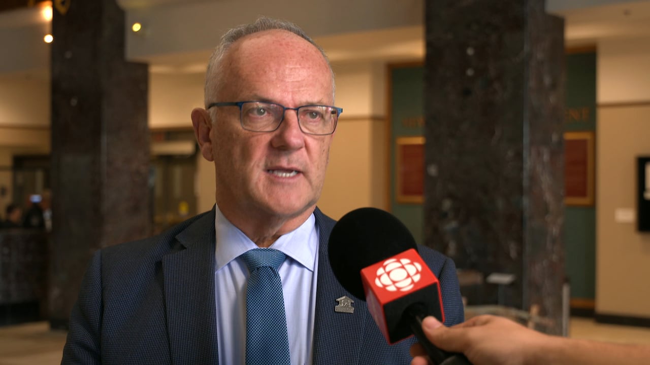 A man wearing a suit speaks into a CBC microphone.