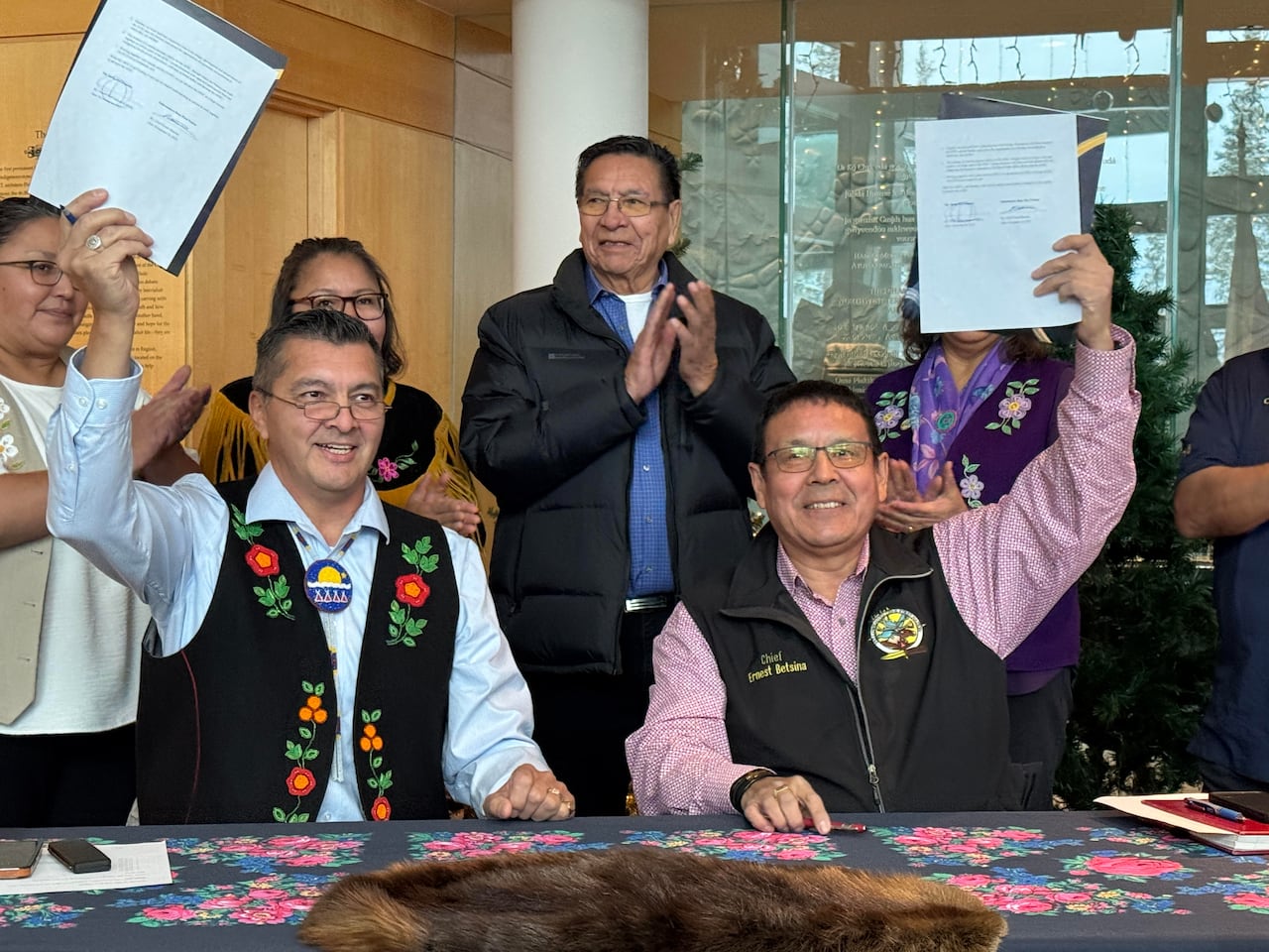 two men hold up documents as crowd behind them claps