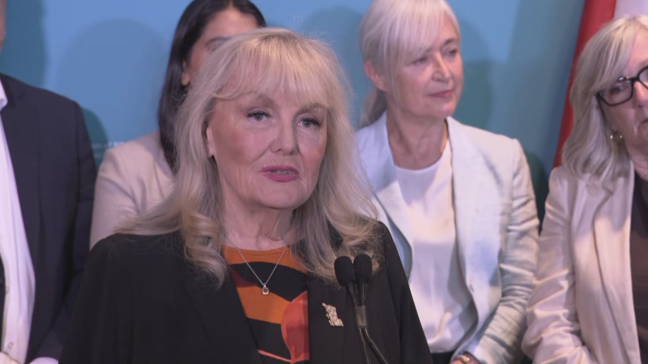 A blond woman speaks at a podium.
