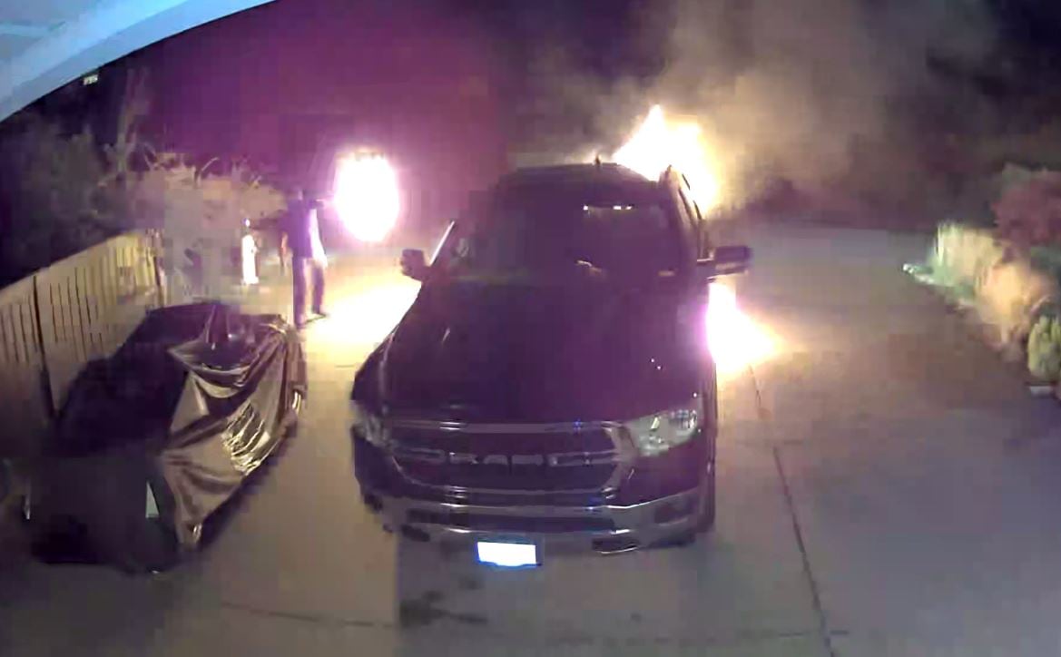 An attacker is seen throwing a flaming rag on a vehicle