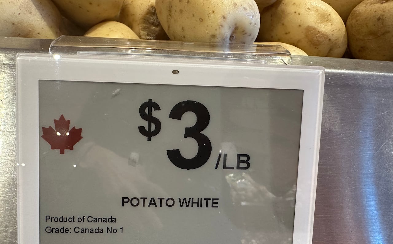 Potatoes in a bin with a sign explaining their cost per pound and country of origin.