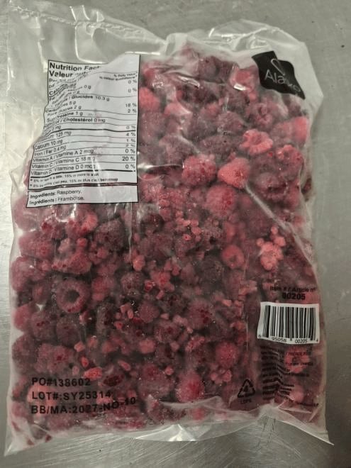 The back of a clear plastic bag containing frozen raspberries.