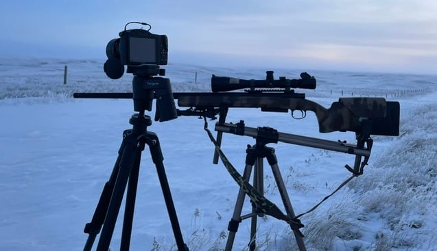 A camera and hunting weapons set up during the winter.