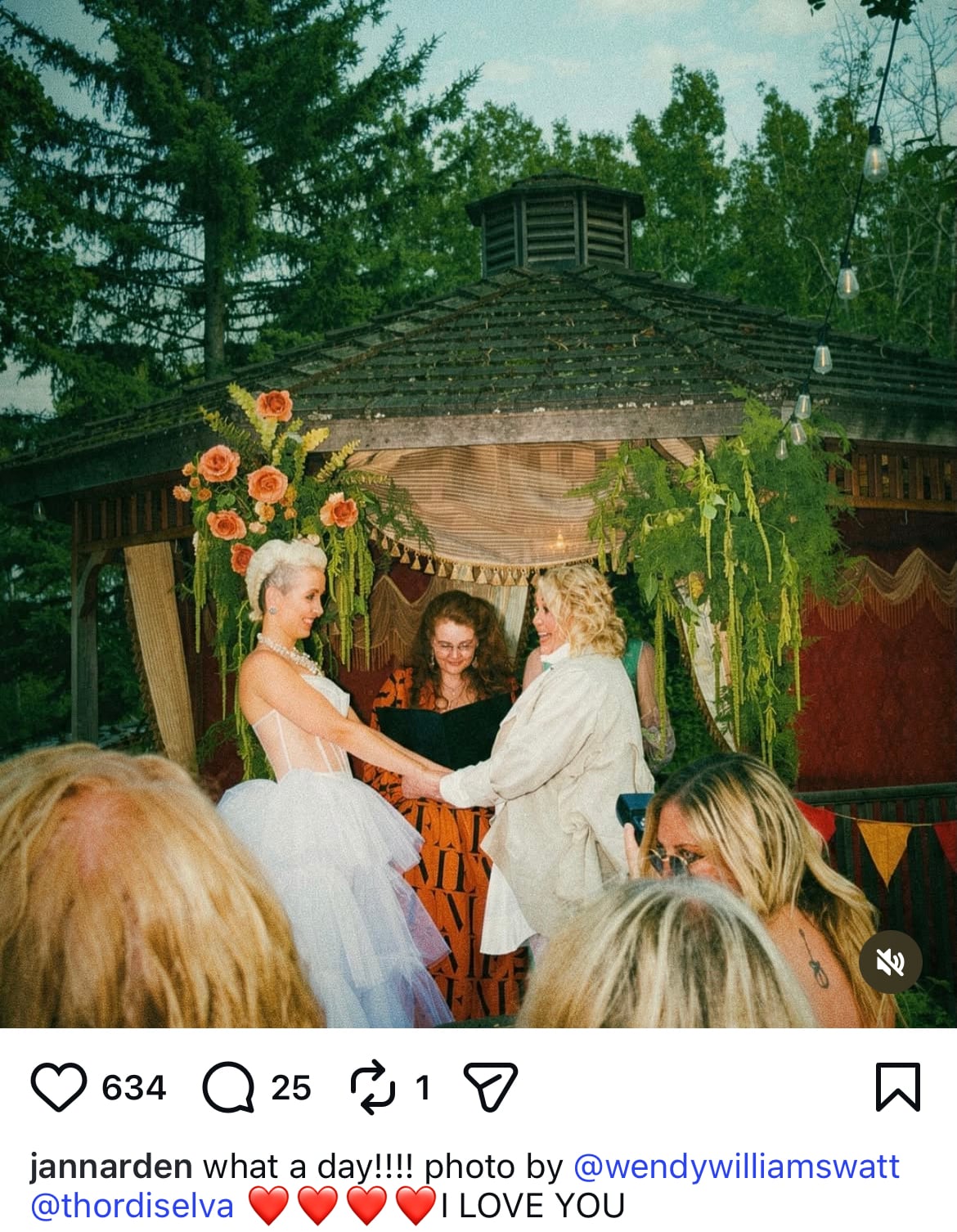 Two people in white hold hands in front of a gazebo