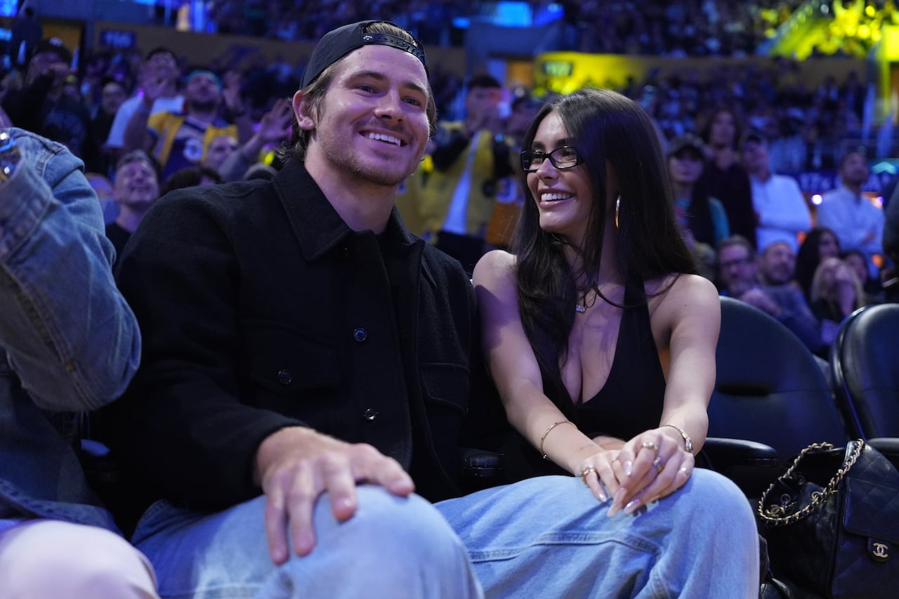 A man and woman sit together, smiling, in a crowded arena.