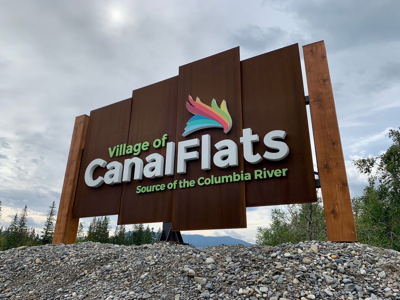 A colourful wooden sign that says Village of Canal Flats, Source of the Columbia River.