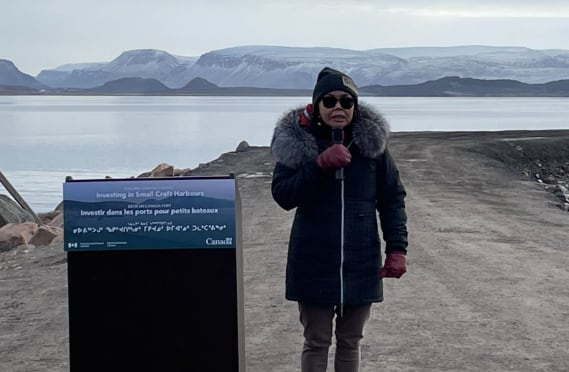 Woman stands by podium outside.