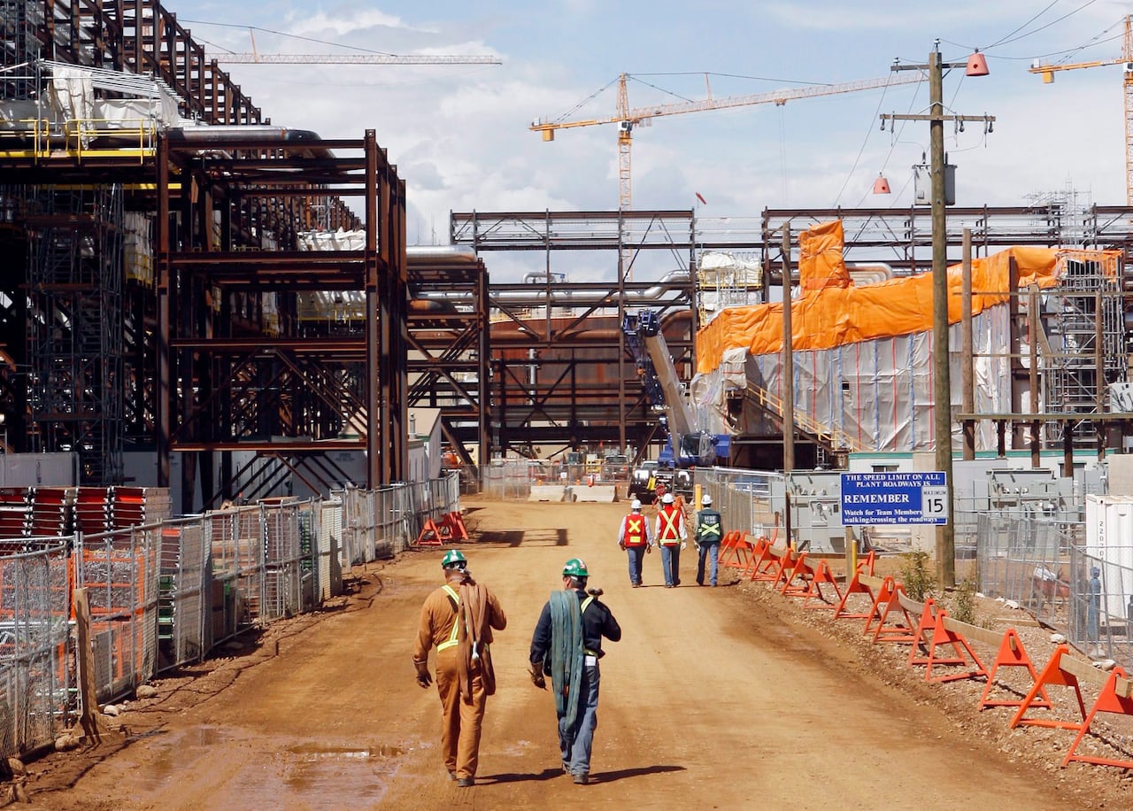 people walking through an in-construction oil facility