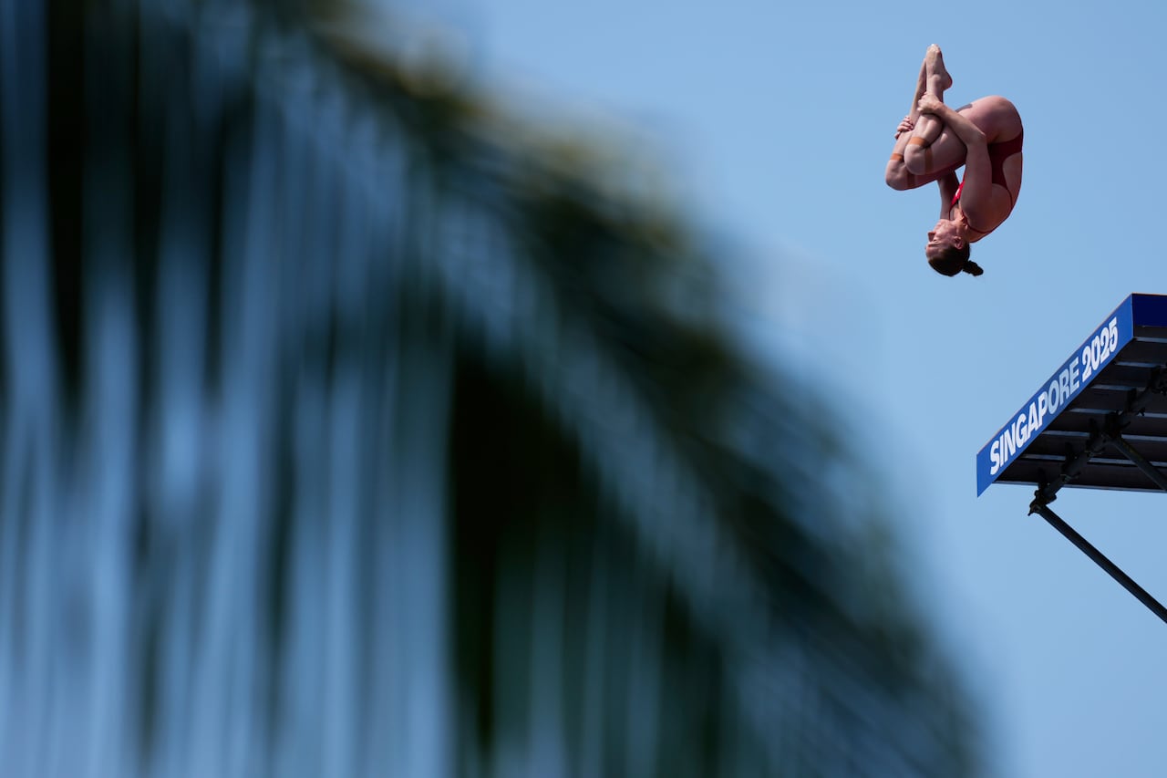 A woman in an upsidedown position after diving off a high board