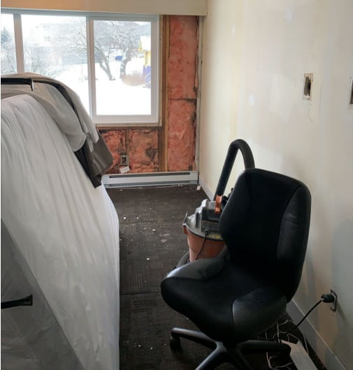 Construction debris and visible drywall and mouldy insulation are seen in a room.