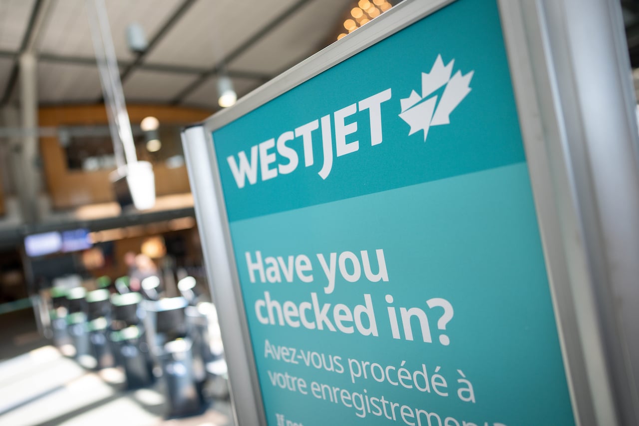 A WestJet check-in sign is shown inside an airport.