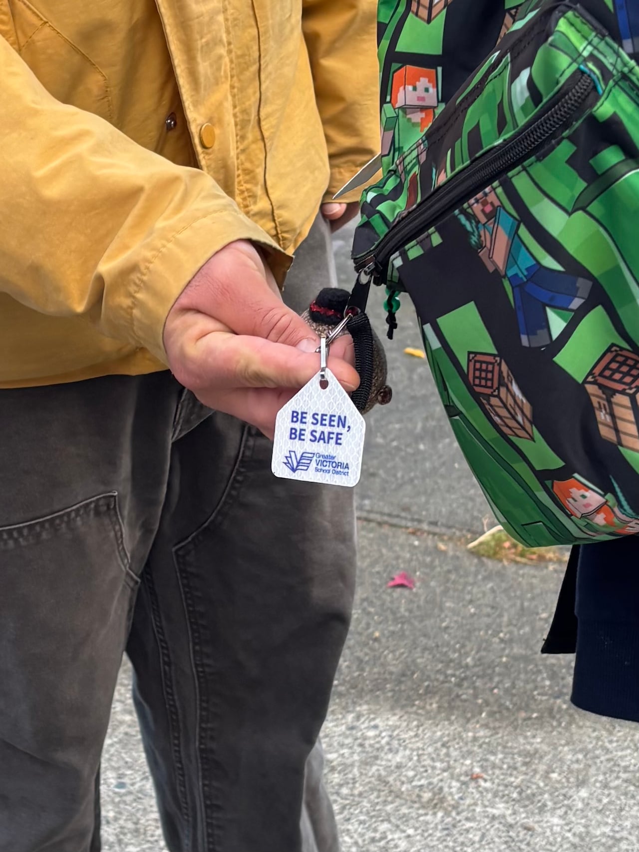 一个小反光片挂在背包上，手指正触碰着它。