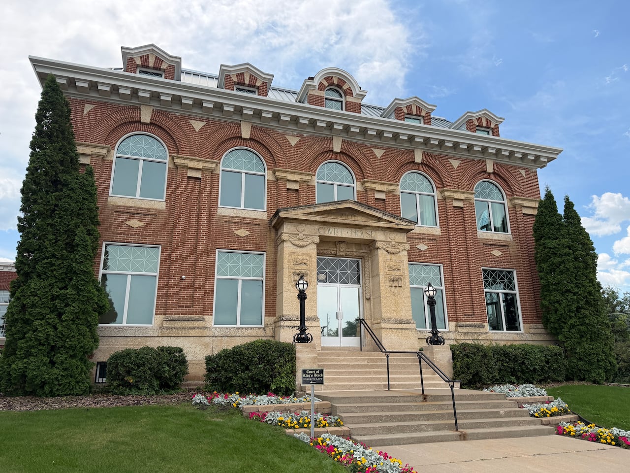 A brick courthouse with flowers outside.