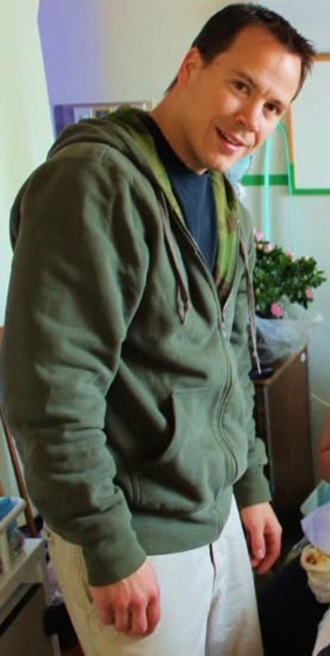 一名男子侧身背对镜头，戴着绿色连帽衫