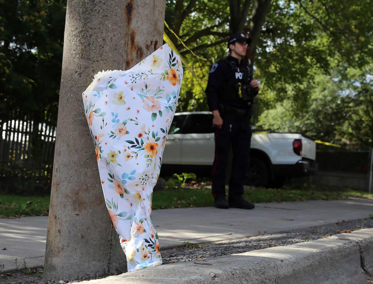A bouquet of flowers on a city sidewalk on a sunny late summer day. A police officer stands in the background.