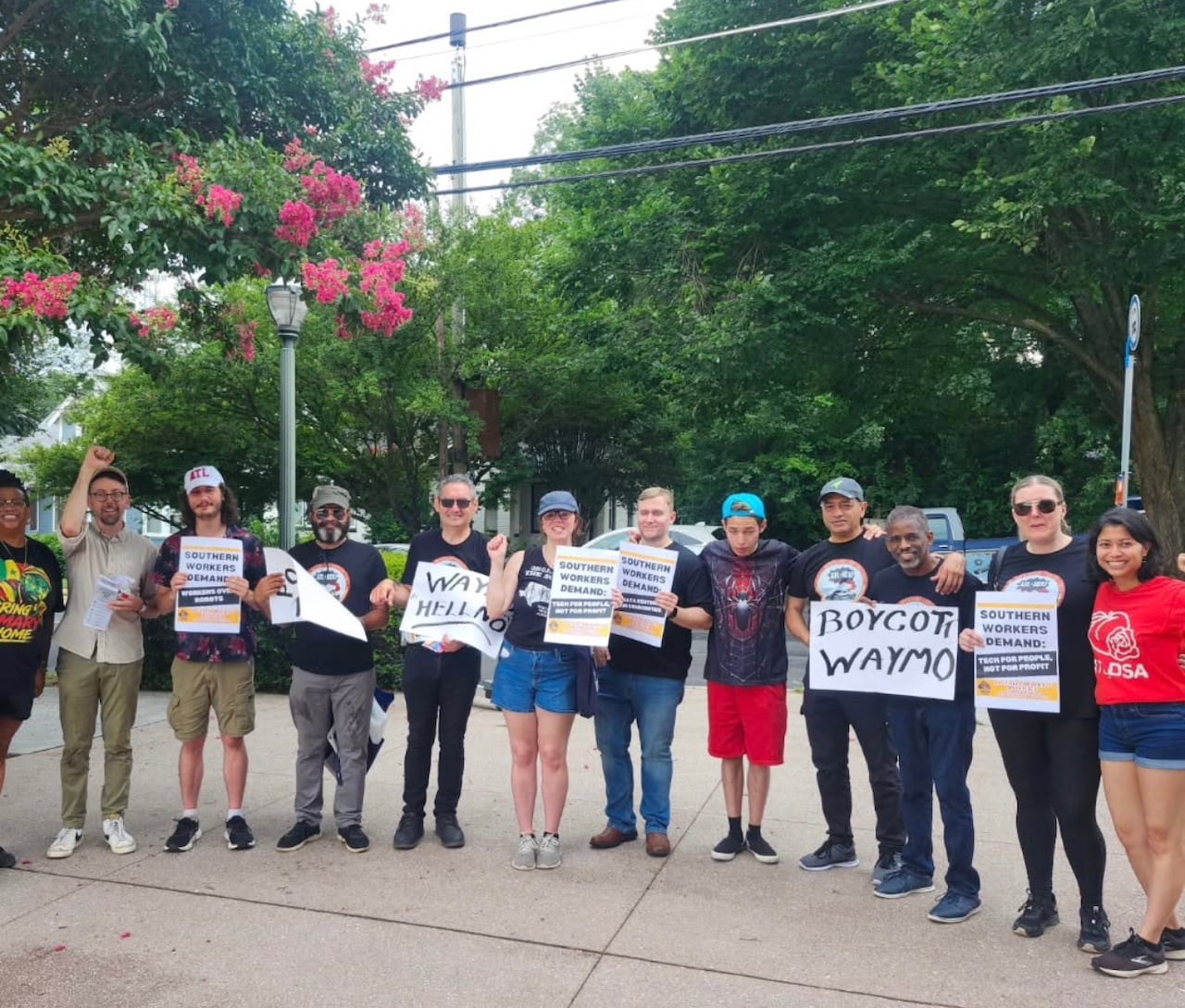 A group of protestors holding signs that say "boycott Waymo" in Atlanta.
