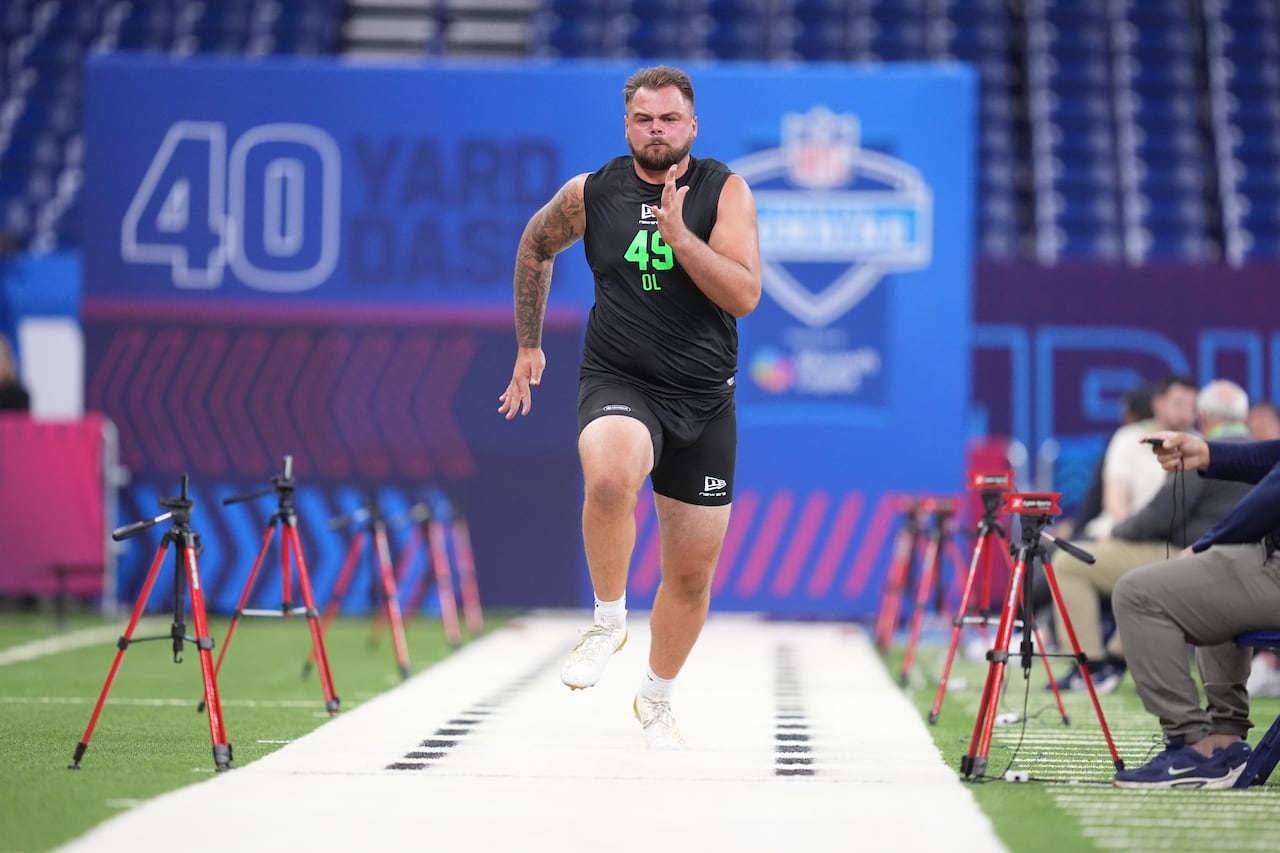 A football player is shown sprinting down a track inside a football stadium as part of the pre-draft combine.