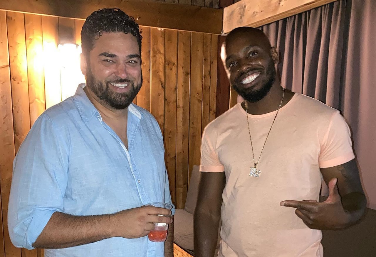 Two men standing outside with drinks.