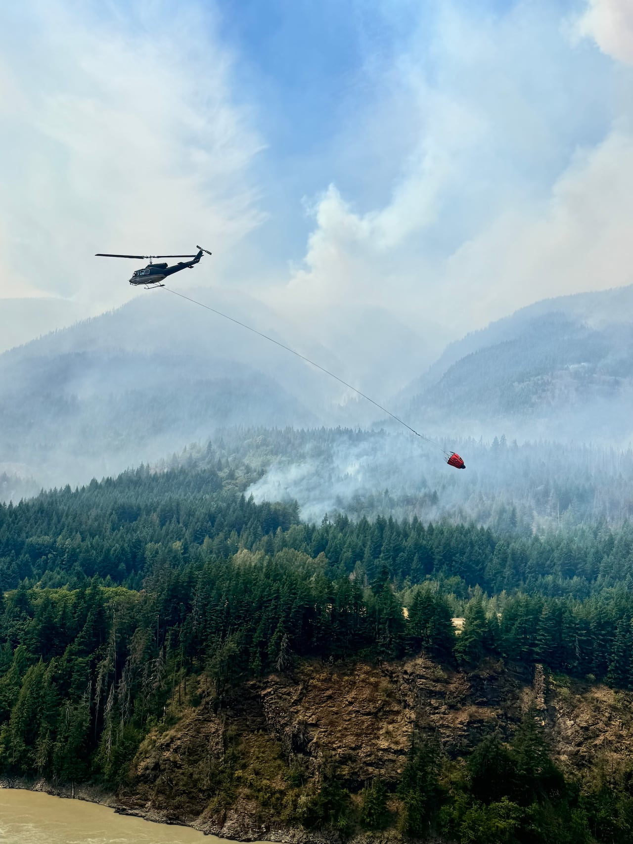 A helicopter flies above a forest fire.