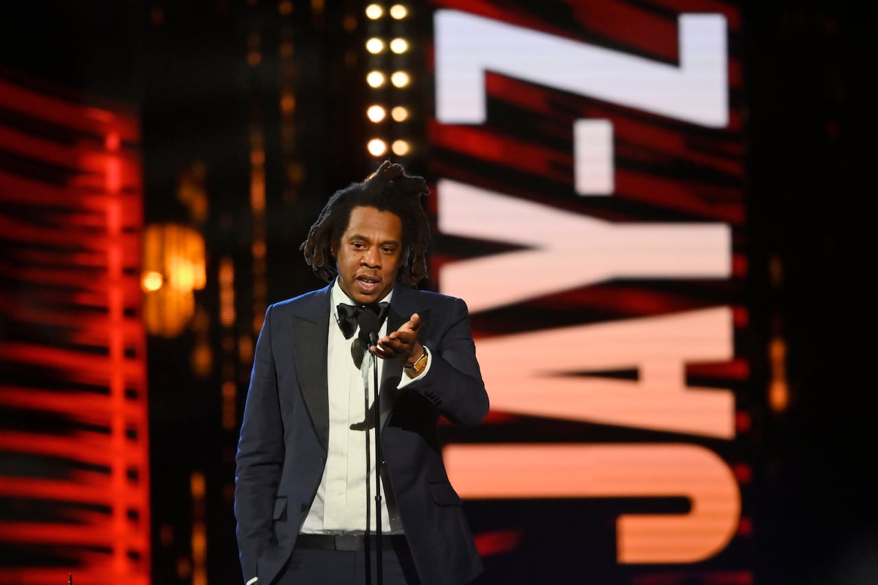 Man with dreads in a tux speaks into microphone