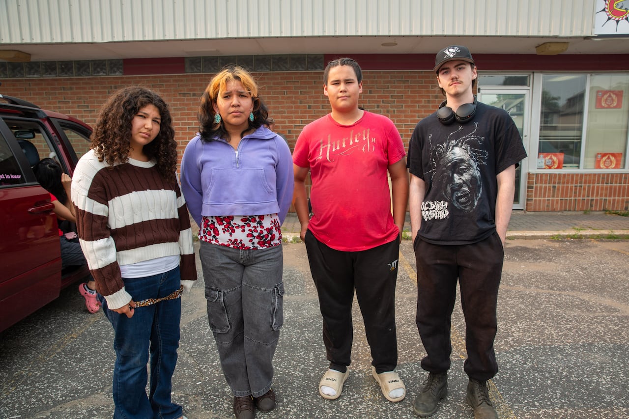 Four young people are seen standing in a parking lot.