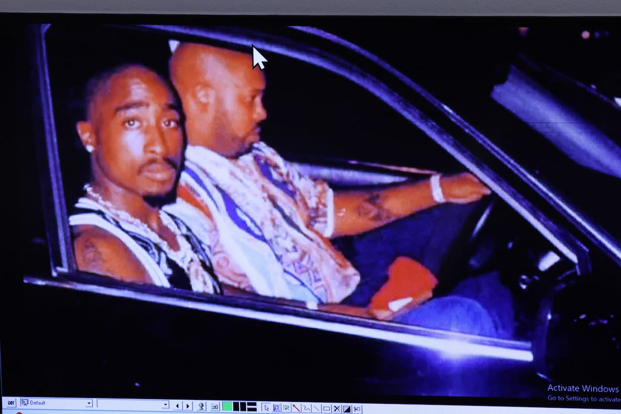 Two Black men seen through the window seated in a vehicle