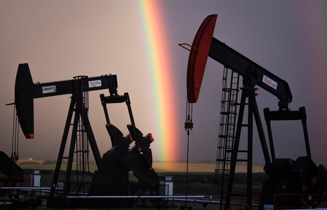 A pumpjack is pictured with a rainbow above.