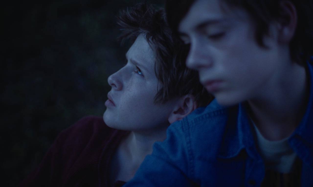 Two boys sit next to each other.
