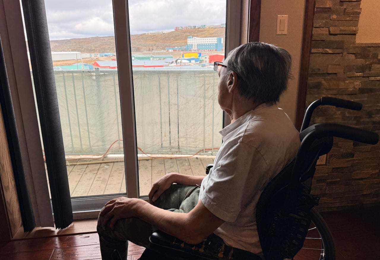 A person in a wheelchair looks out a window.