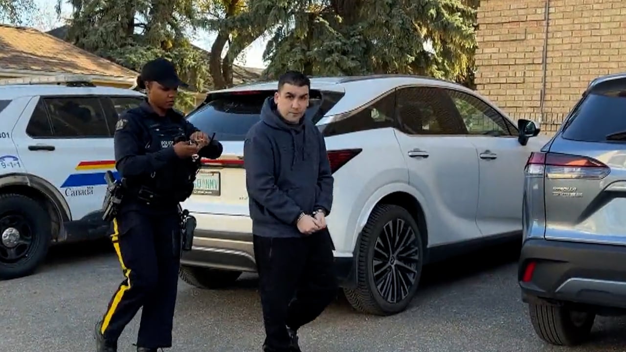 Man walks in handcuffs with a police officer behind him.