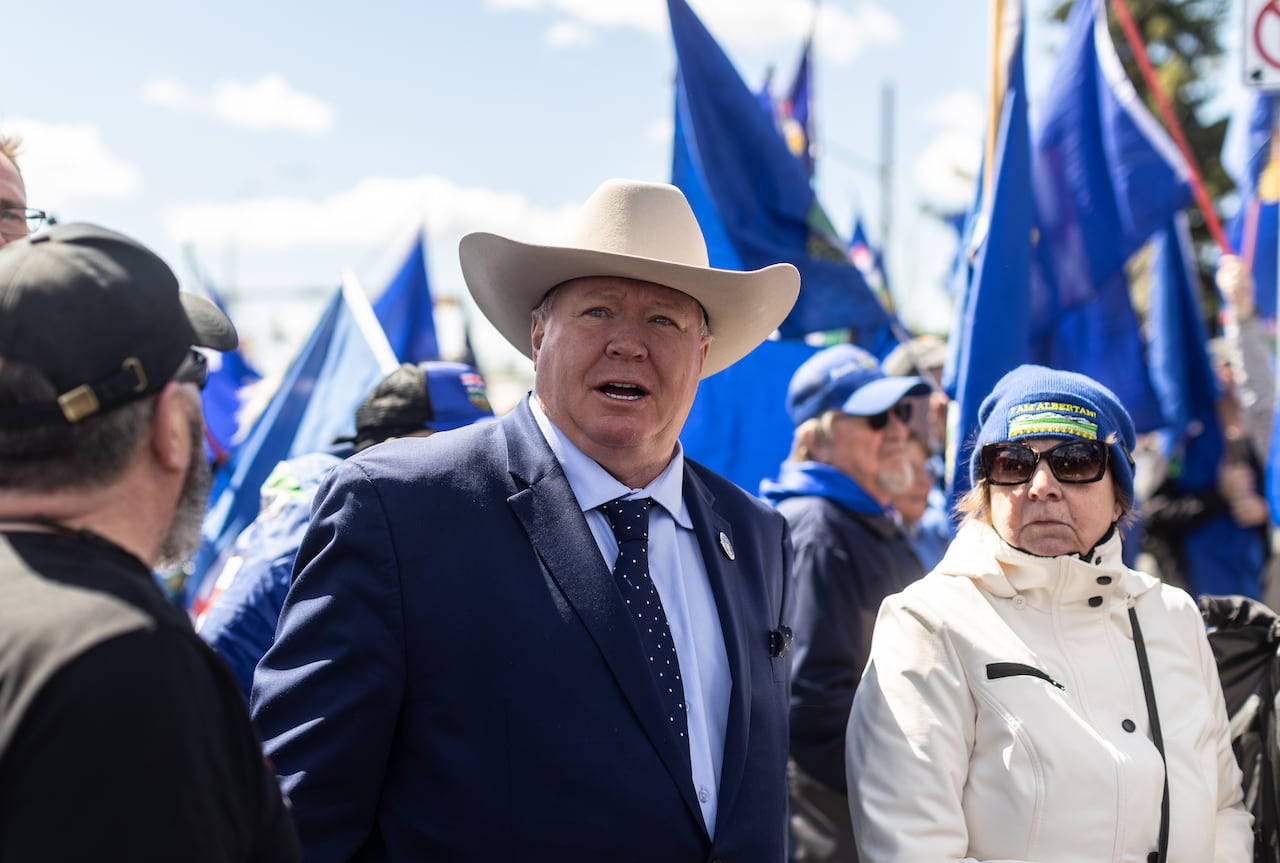 Man in cowboy hat around Alberta flags.