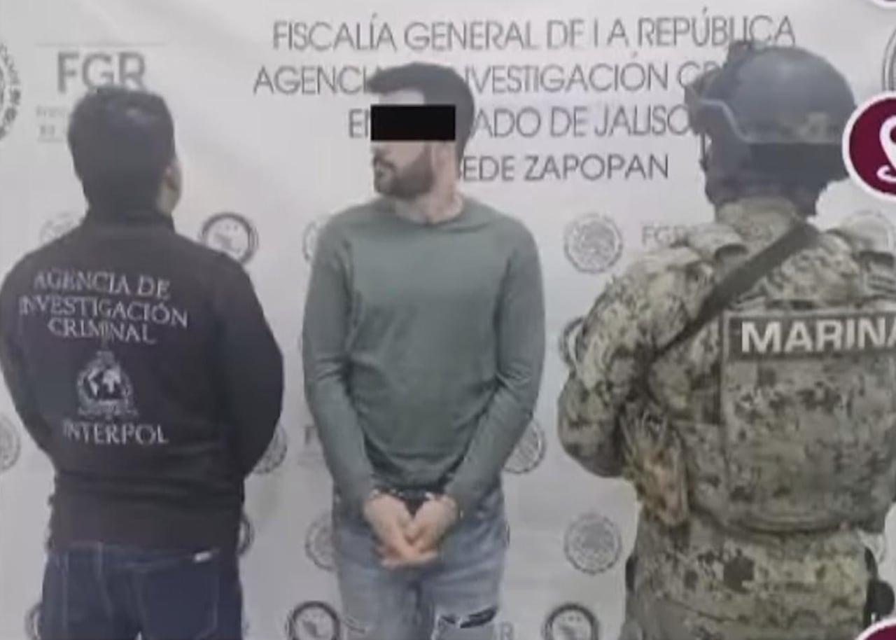 一名被手铐铐住的男子被身穿刑警及军装人员押解