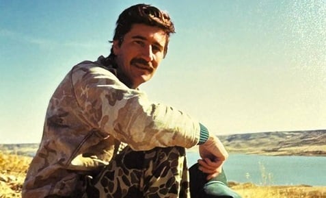 Erickson in hunting clothing posing with his gear.