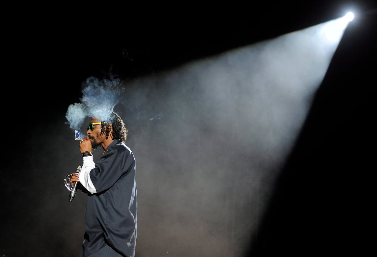 A man standing in a spotlight smoking.