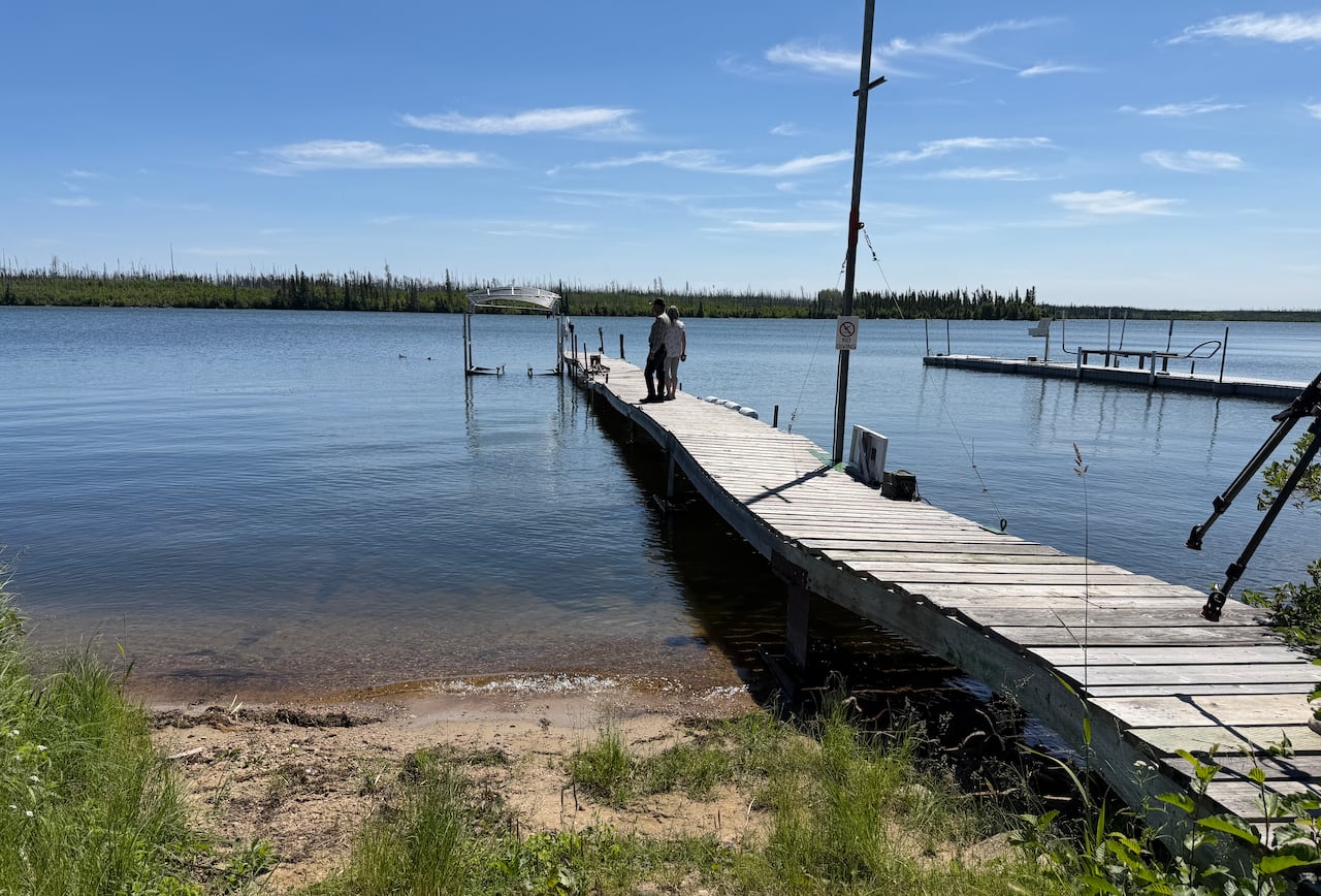 Two people on a dock on a lake.