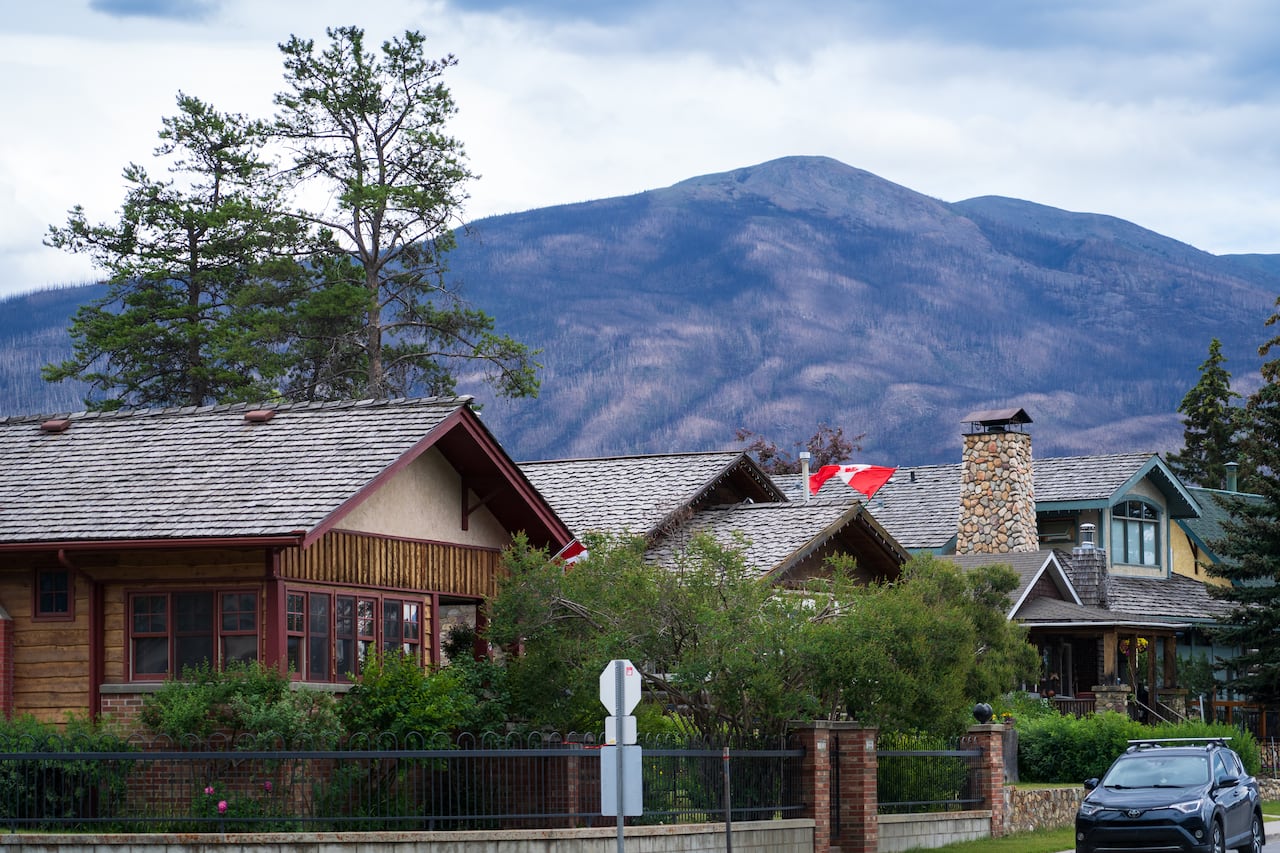 Three two-storey homes with cedar-shingled roofs sit in the foreground of a mountain backdrop in the Jasper townsite.