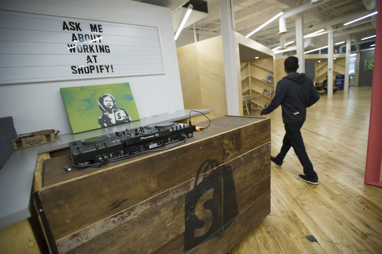 A man walks past a DJ booth at a Shopify office in Toronto