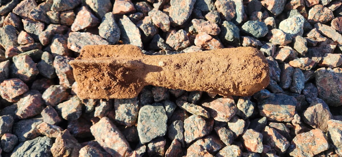 What looks like an old explosive munition is seen sitting on rocks.
