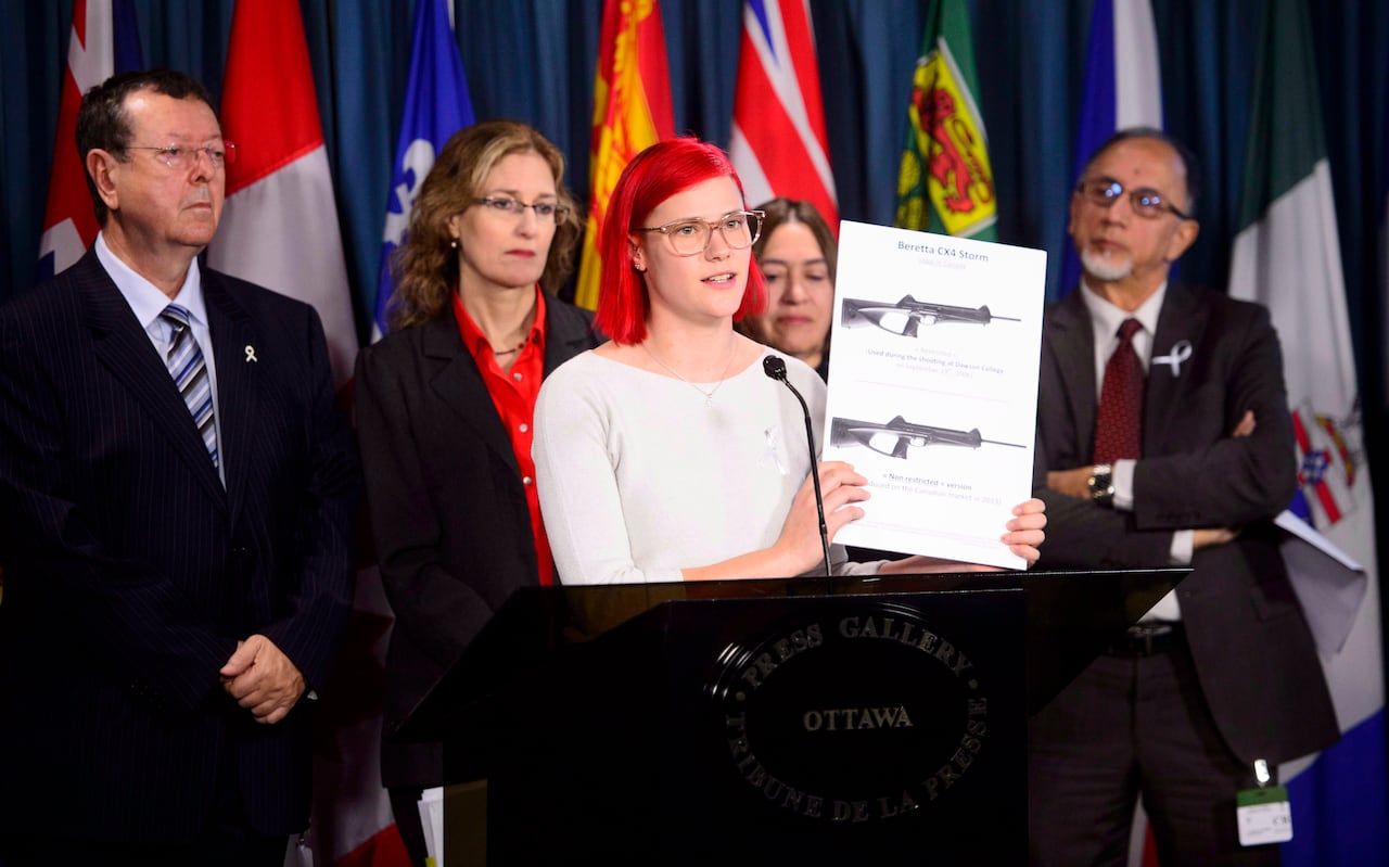 Meaghan Hennegan who was shot twice during the Dawson College shooting holds up a board showing assault weapons as she joins other gun control advocates as they hold a news conference on Bill C-71 on Parliament Hill in Ottawa on Monday, Dec. 3, 2018.